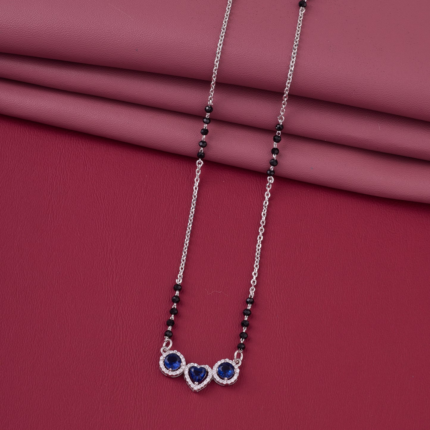 elegant silver-tone mangalsutra with black beads and triple blue stone heart pendant